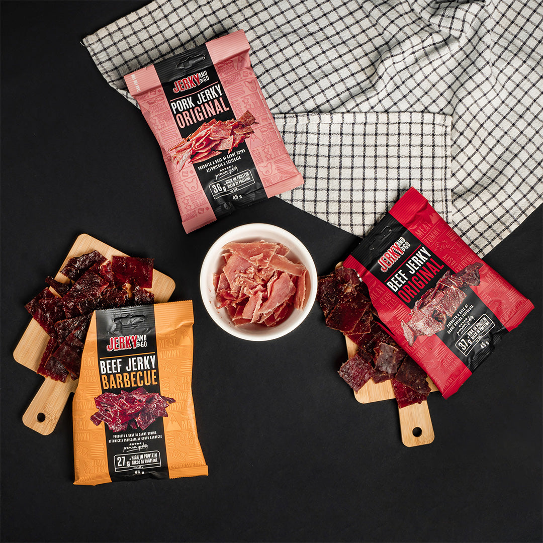 foto ambientata di tre pacchetti di carne secca Jerky and go al gusto barbecue, original e maiale